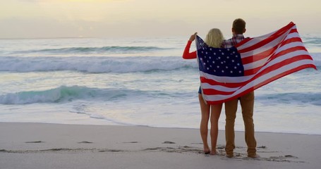 Couple standing with American flag at beach - Powered by Adobe
