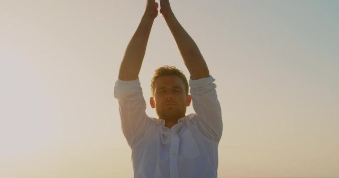 Man doing yoga on beach during sunset