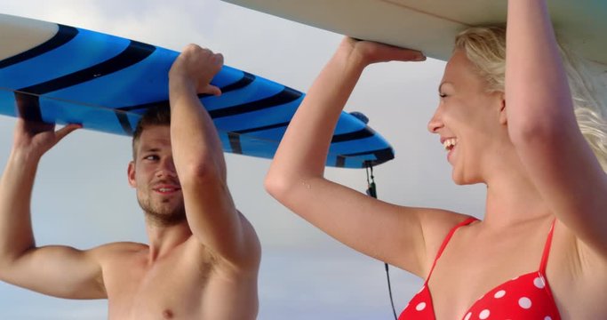 Couple carrying the surfboard on their head at beach