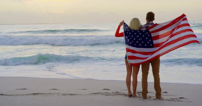 Couple standing with American flag at beach