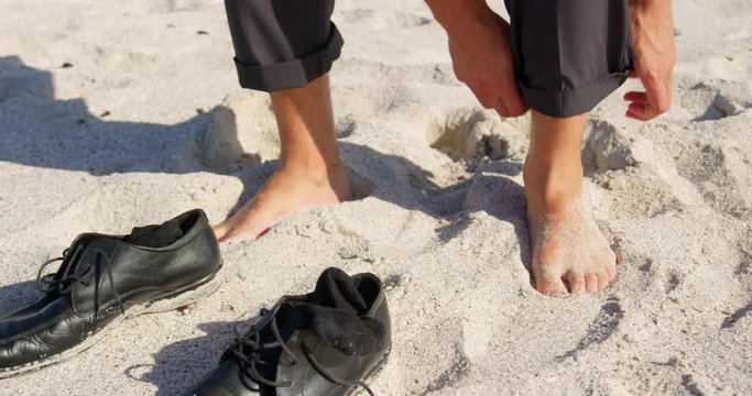 Businessman rolling up his pant on beach in the sunshine