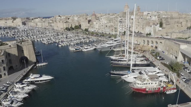 Aerial view of sailboats moored in harbour Senglea and Birgu, Bormla / Cospicua, Valletta, Malta. Ancient architecture of old town: christian orthodox churches, cathedrals, basilicas. Sunny day, blue 