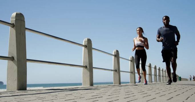 Fit couple jogging on a promenade at beach