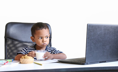 The little Asian boy sitting and watching his computer. Concept of online learning. Soft focus.