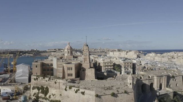 Aerial pan up view of Senglea, Bormla, Valletta old architecture, ancient churches, fortress, cathedral, bell towers, harbour with sailing boats. Malta from drone. Travel destination. Summer sunny day