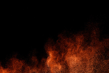 Abstract explosion of orange dust on black background.Freeze motion of orange powder splashing.