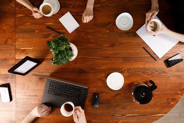 Group of business people working at desk, top view. Weekday work concept. Office stuff and gadgets nearby.
