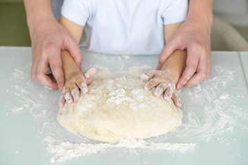 hands of a child and dad cook from dough