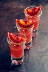 Strong red cocktail in shots on the rustic background. Selective focus. Shallow depth of field.