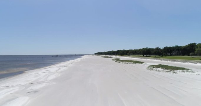 Pass Christian Beach, flying low over the sand and rising to reveal main road with cars and cyclist