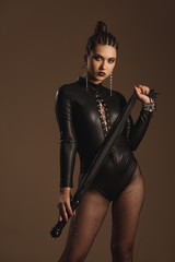 Fototapeta premium Attractive hot girl in leather suit and cuffs isolated on white