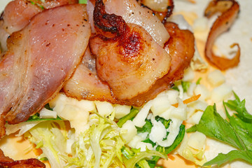 Leafy salad, sliced vegetables, sauce and fried bacon slices on pita bread are the basis for homemade Shawarma. Close up.