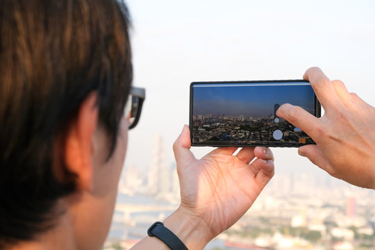 Young people take pictures of the buildings in the city. Sunrise time He uses a high-angle recording photo phone.Travel concepts and technology