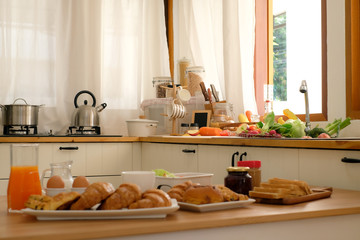 Many breads and orange juice, salad and fruits,vegetables to prepare for breakfast in the kitchen.