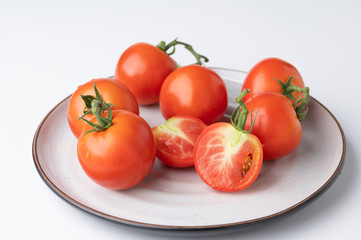 Fresh tomatoes on a green stem on white background