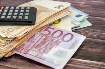 stack with euro banknotes with a calculator on a wooden background. Business concept.