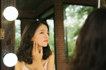 Reflection in the mirror. Woman looks in the mirror noticing the first wrinkles