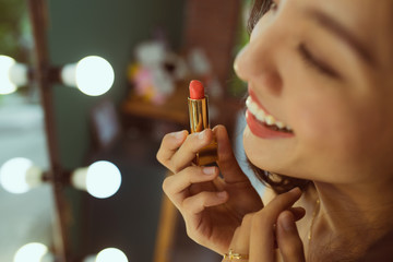 Woman applying lipstick looking at mirror. Beautiful girl makes makeup