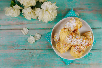 Homemade puff pastry cones filled with caramel cream on wooden background.
