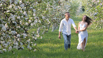 Obraz premium young guy and girl in blooming apple trees in the garden
