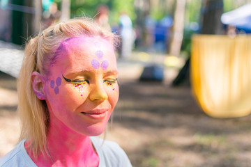 A woman's face painted in a fairy-tale character. Applying a pink aqua-color to the face.