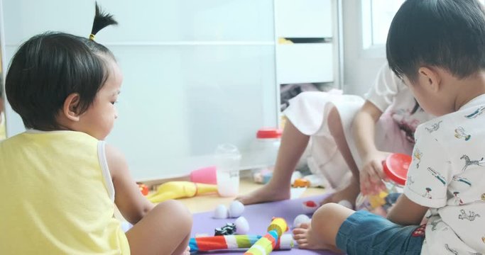 Children and toddlers group play logical toy learning shapes, arithmetic and colors at home