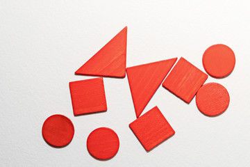 Different red shapes wooden on white background. Top view. Concept of geometry. Copy space....