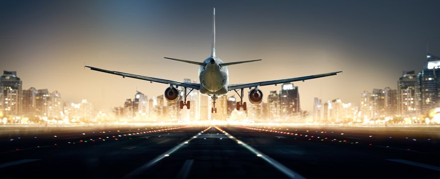 Flugzeug landet bei Nacht in einer Gro&szlig;stadt