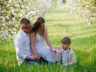 family with a child in blooming apple trees in the garden