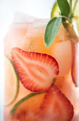 summer cocktail with lime and strawberries and a sprig of sage