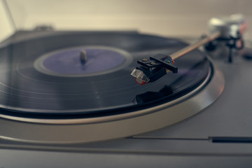 The vinyl needle reads the music from the record on a vinyl player. Old school. musical atmosphere....