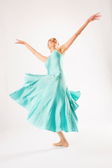 Fototapeta na wymiar Adult woman dancing in the studio in a blue dress.