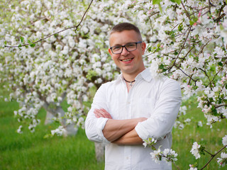 young handsome smart man agronomist in a flowering garden