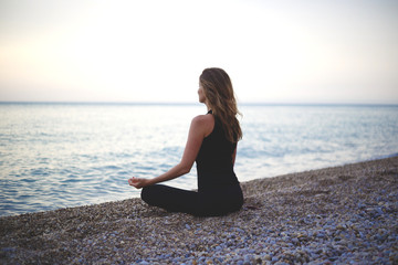 Fototapeta na wymiar woman doing yoga at sunset on the beach