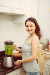 Vegetable smoothie woman blending green smoothies with blender home in kitchen