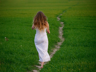 girl in a long white dress on a green field