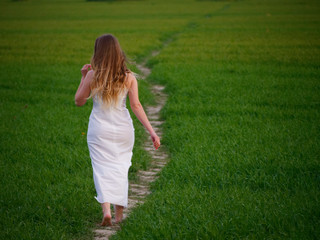 Naklejka na ściany i meble girl in a long white dress on a green field