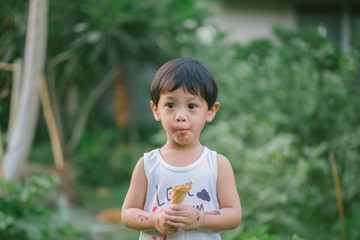 Asia boy he mouth aftertaste from eating chocolate ice cream  or chocolate dessert. A sweet-toothed child eat chocolate. Kid with dirty face eating ice cream. Cute toddler boy eating icecream.