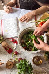 A multi-tasking mother prepares lunch and checks her daughter’s lessons and plays with the baby at the same time during the isolation period.