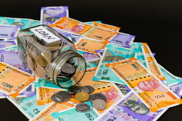 High angle close up shot of a glass jar with coins and money notes for loan concept.