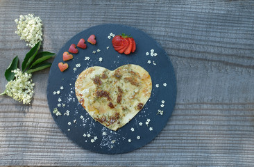 High angle shot of heart shaped pancake with sambucus flower. Garnished with five heart shaped red...