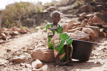 Poor African Woman Sitting Outdoors with Water Bucket