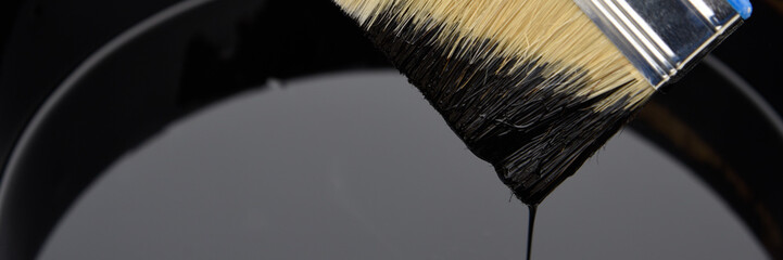 Roofer's hand holding a brush with bituminous mastic