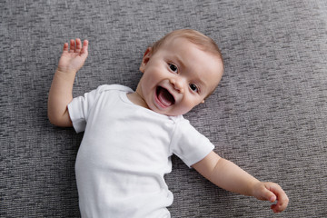 Happy baby lying on grey couch