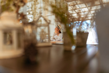 Portrait of stylish young woman in dress vintage style and hat sit posing in the coffee shop decoration in vintage style