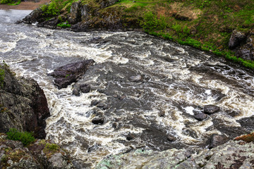 Beautiful landscape with big stones in water riffle of mountain river. Powerful water stream among boulders in mountain creek with rapids. Fast flow among rocks in highland brook. Small river close-up