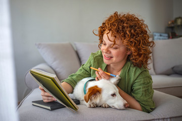 Woman working at home. Freelance working. Young afro-american woman sitting with her pet dog and study at home. Woman working from home in the company of her puppy