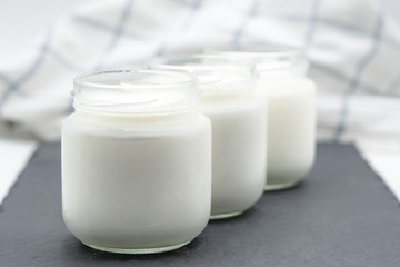 Three glasses of yogurt on a slate plate on a white background