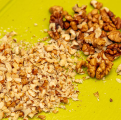 Knife-chopped walnuts on a green plastic board.