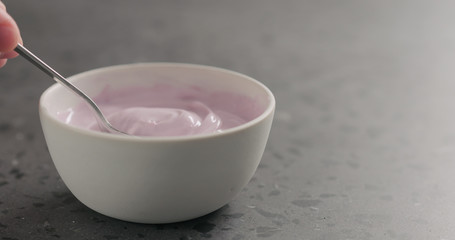 man hand scoops blueberry yogurt from white bowl with copy space